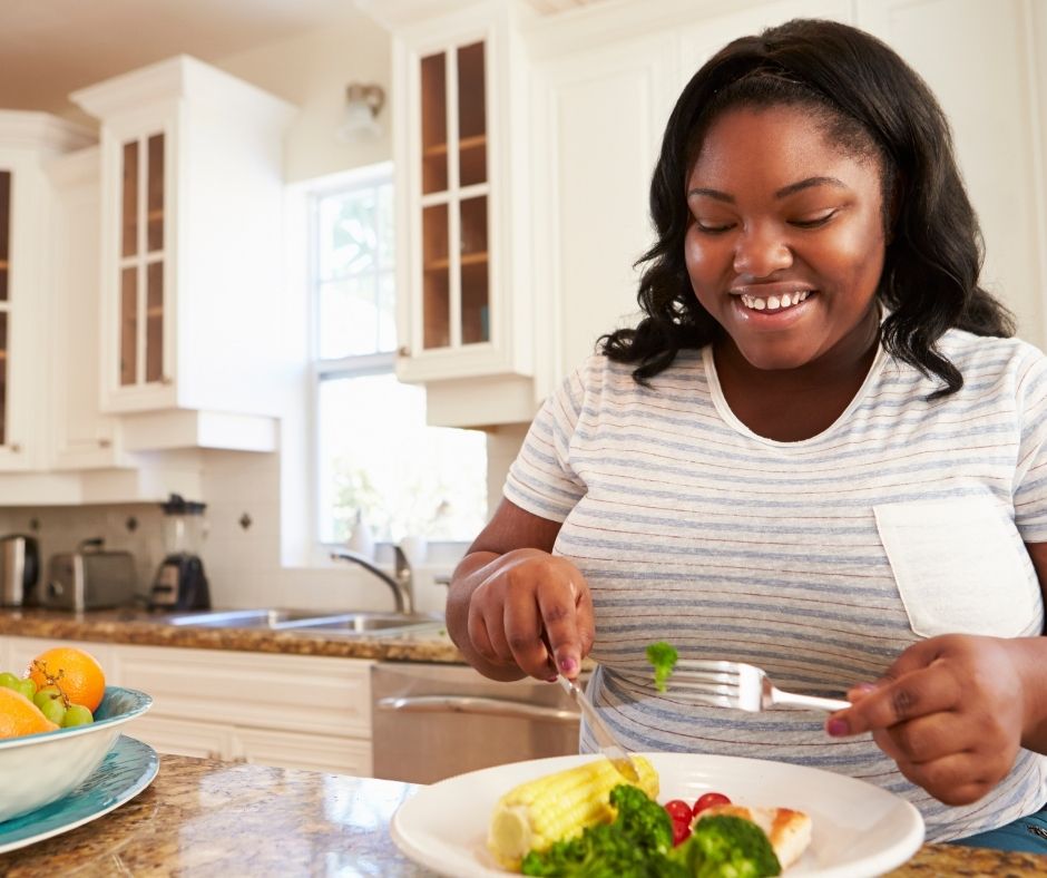 woman in kitchen eating a healthy meal